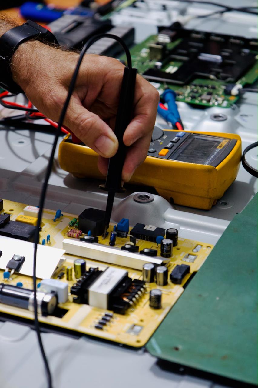 TV aberta em manutenção, com a placa sendo testada